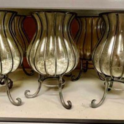 Lot 045-GAR: Glass/Metal Hurricane Candleholders

Features: 
•	A set of 10 clear, curvaceous glass hurricane candleholders, each nestled...