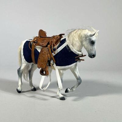 MINIATURE SADDLE & HORSE FIGURINE | White horse figurine with blue coat and a detailed tooled leather miniature saddle signed...