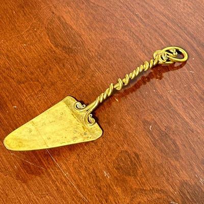 SIGNED BRASS CAKE SERVER | Double turned and scrolled handle, signed “Joe Spoon” or “Jae Spoon” and dated ‘85. - l. 10.75 in

