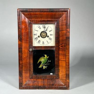E.N. WELCH SHELF CLOCK | Having a burl veneered case with eglomise painted panel of a bird, the face with Roman numeral markers. - h....