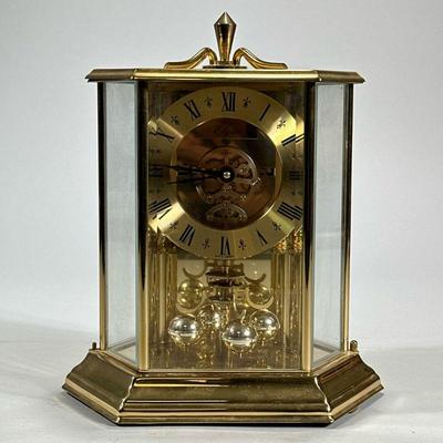 ELGIN BRASS MANTEL CLOCK | Made in Germany, anniversary clock in a hexagonal brass and glass case with torsion pendulum. - h. 9.5 x w....