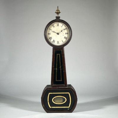 ANTIQUE BANJO CLOCK | With black and gilt reverse painted glass, brass finial, white face with Roman numerals. - h. 32.5 x w. 11.25 x l....