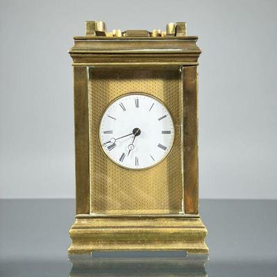 “AB” BRASS CARRIAGE CLOCK | Heavy, with beveled glass panels, white face set in a brass engine-turned panel, having Roman numeral...
