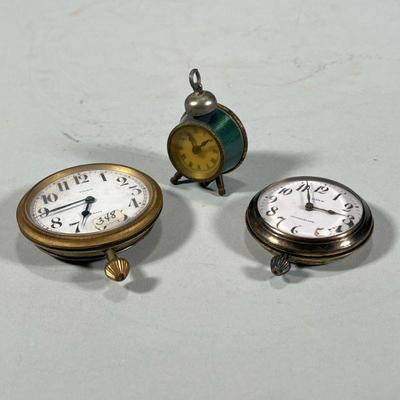 (3pc) MISC. SMALL CLOCKS | Including a miniature green alarm clock, a Swiss 8 day clock, and a Kenzie 8 day clock / watch (h. 3-1/8 x...