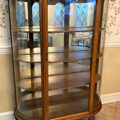 Antique oak china cabinet with curved glass.
