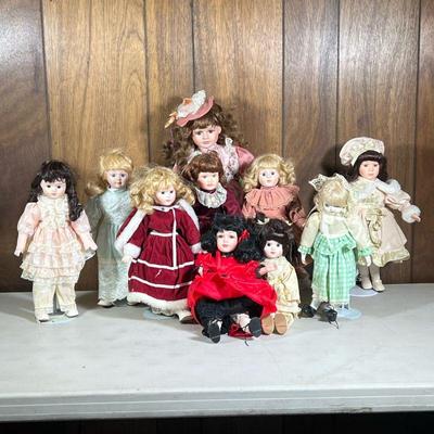 (10pc) Porcelain Head Dolls | Some on stands, including a Noble Heritage Collection doll in red velvet dress, a Brinn’s 1990 doll, a...