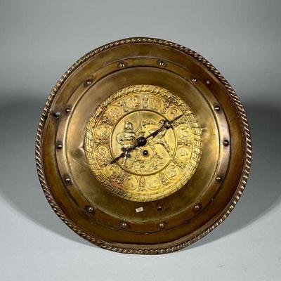 PRESSED BRASS FACE CLOCK | The face decorated with a battle scene of two medieval soldiers in a sword fight, with Arabic numerals. - d. 3...