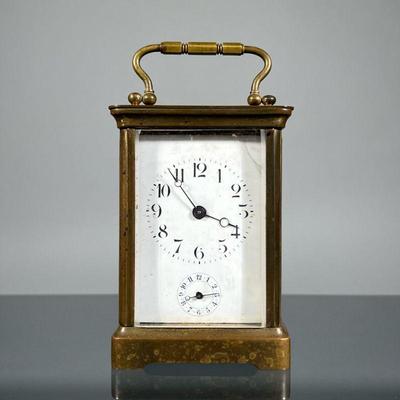 H&H FRENCH CARRIAGE CLOCK | In a brass case with beveled glass and an oval top window, the face with Arabic numerals and sub-dial,...