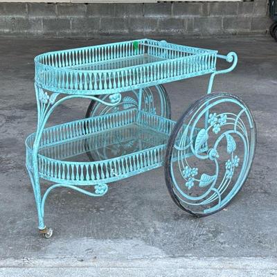 MID-CENTURY PATIO BAR CART | Cast iron bar cart with two glass shelves, having scrollwork and intricate vine design wheels. - h. 32 x w....