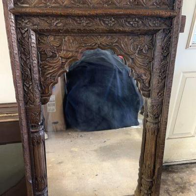 This is a vintage, intricately carved wooden mirror with a distinct rustic aesthetic. The frame features ornate detailing, including...