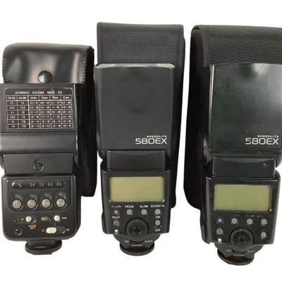 TICA218 Three Canon Speedlight Flashes	2- 580EX speed lite flashes. Both come with a case. 1-300TL speed lite flash. Comes with a case.
