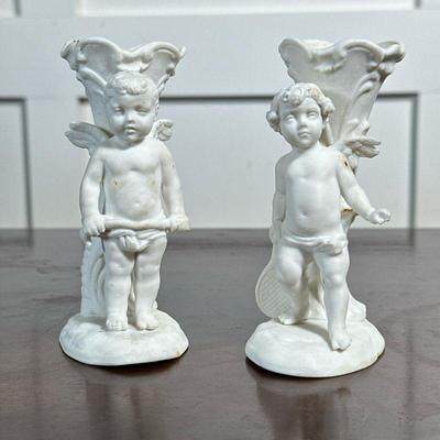 (2pc) PAIR PORCELAIN CUPID BUD VASES | Pair of porcelain bud vases with Cupid figure, each numbered on the bottom - h. 4.5 x w. 2 x d....