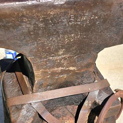 Large, heavy vintage anvil strapped on an old block of wood.