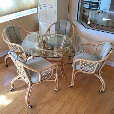 Rattan dinette or lanai table with 4 rolling chairs. Howard Miller bar cabinet in background