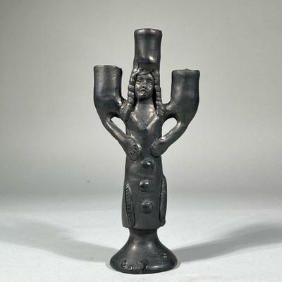 FIGURAL POTTERY CANDLESTICK | An unusual figural pottery candle stick holder of modern style designed as a female figure with feathers on...