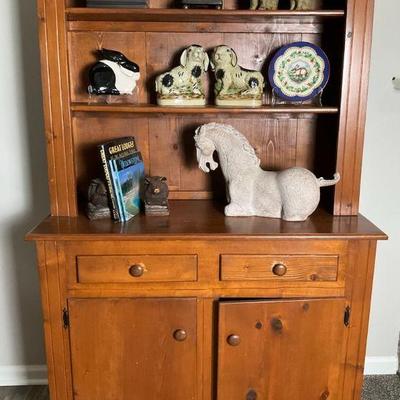 Rustic pine hutch with ceramic animal figurines and decorative plate