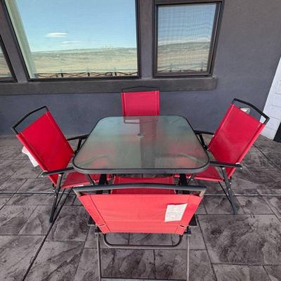 Lot #192 - Patio Dining Set - Glass Top Table with 4 Red Folding Chairs