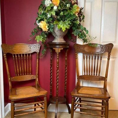 Two cane side chairs with pedestal table and floral arrangement
