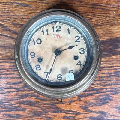 Wall Clock | Round wall clock with Arabic numeral markers, the face marked with a red "D" inside a flag. - ia. 8.25 in (Overall)

