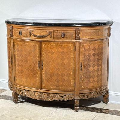 French Style Satinwood Cabinet | Demi-lune parquetry server cabinet with carved and contrasting inlaid wood, having a black marble top...