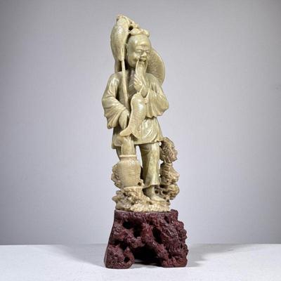 CARVED STONE FIGURE | Carved jade or stone Chinese figure of a fisherman on a contrasting stone carved base. - h. 14 x w. 4.5 x d. 3.5 in

