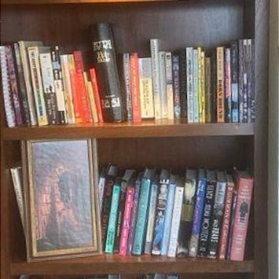 Bookcase full of fiction nonfiction books & framed prints