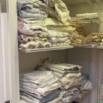 A closet full of linens ironing board & other items