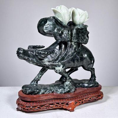 CHINESE JADE CARVING OF AN OX WITH BLOSSOMING LOTUS | Jade OR serpentine; a finely carved Chinese stone sculpture depicting an ox...