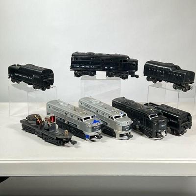 (8pc) LIONEL LOCOMOTIVES & COAL CARS | Including two silver locomotives, two black locomotives, three cold cars, and one with no top.