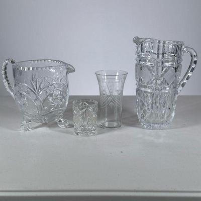 (4pc) Cut Crystal | Including two pitchers, one having scroll feet, a glass, and a small votive holder. - h. 8.5 x w. 6.75 in (largest)


