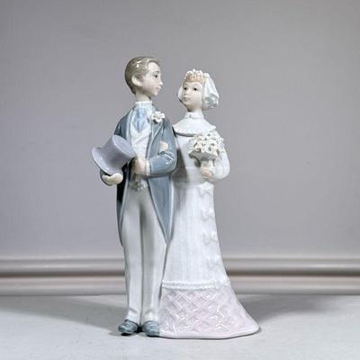Lladro Bride & Groom Figural Group | Groom holding top hat, arm in arm with bride and her bouquet, marked on bottom. - h. 8 x l. 4 x...