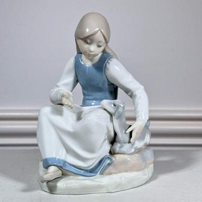 Girl with Goat | A LLadro-style porcelain figurine of a young girl feeding a goat in shades of blue, gray and white, numbered on bottom....
