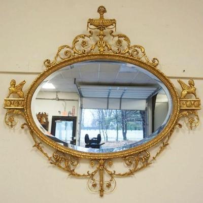 1169	FREIDMAN BROTHERS OVAL BEVELED EDGE MIRROR IN ORNATE GILT FRAME WITH WINGED GRIFFINS AND URN AT CREST, APPROXIMATELY 50 IN X 48 IN H
