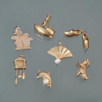 "(8pc) GROUP OF 14K GOLD CHARMS | Including a sailboat (marked 14k); an articulating cuckoo clock (no apparent mark); a poodle...