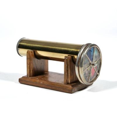 "JANICE CHESNIK KALEIDOSCOPE | Handmade brass kaleidoscope, signed and 1986, on a conforming wood stand
 - l. 6.75 x dia. 3 in."