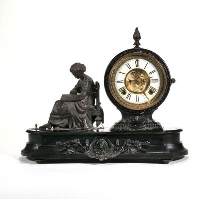 "ANSONIA CLOCK CO. FIGURAL MANTEL CLOCK | Having cast metal figure of woman reading 
h. 14 x l. 17 x d. 7 in."