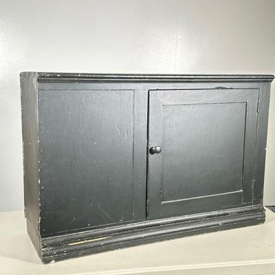 Vintage Black Cabinet | Possibly an old mounted cabinet from kitchen. Painted black with one knobbed door. Dimensions: h. 23 x w. 35 x d....