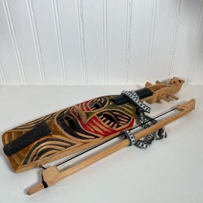 (2pc) African Instrument | Carved wooden string instrument with bow. Face is colored. No markings. Dimensions: h. 20 x w. 6 in.
