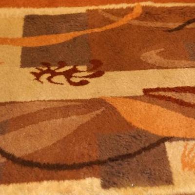 Mid century style area rug in orange browns and cream color. 