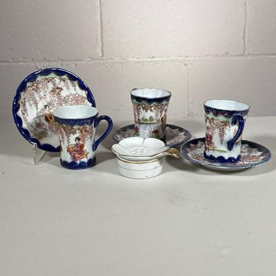 (8pc) Japanese Tea Cups | Blue rimmed cups and saucers with geisha girls. Tea strainer marked Japan. Dimensions: h. 3 x dia. 2.5 in (Tea...