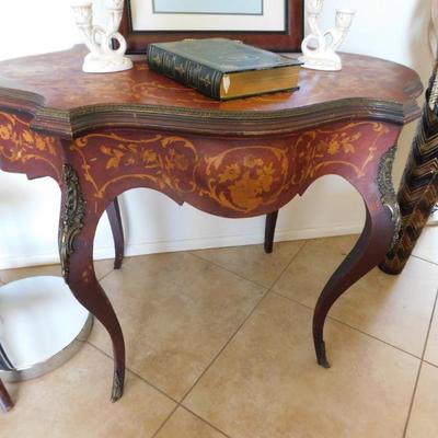 Sale Photo Thumbnail #43: An Edwardian Marquetry Turtle Table, with complex inlay of boxwood and mother of pearl.. Conforming skirt with shaped edge and matching inlay. Cabriole legs having gilt ormulu portrait mounts.
