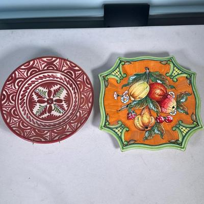 (2pc) DECORATIVE HANGING DISHES | 2 decorative hanging dishes including: Sanguino luster glazed bowl, and Dip. A Mano fruit-decorated...