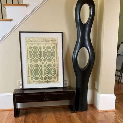 Framed Geometric Print, Glossy Black Bench, and Tall Modern Sculpture