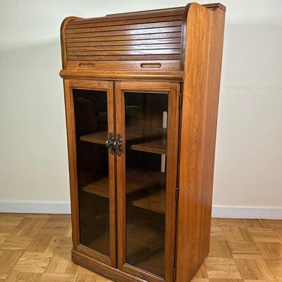 Roll-Top Display Cabinet | Vintage (mid 20th c.) tall roll-top display cabinet with glass doors, inner shelves, and decorative hardware....