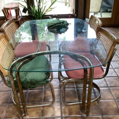 Glass Top Dining Table With Metal Base And Wicker Chairs
