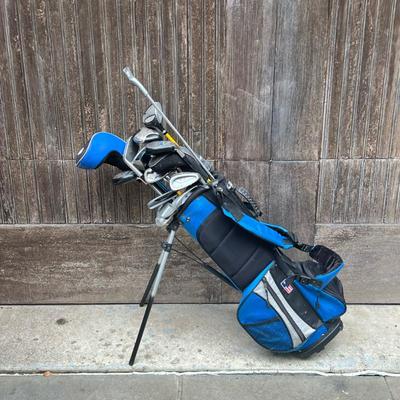 US Kids Golf Bag And Clubs | Size 45-31 with multiple pockets and stand. Many clubs included. - h. 24 x w. 9 x d. 7 in (Top of bag)
