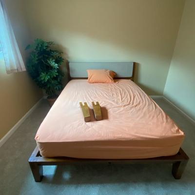 Platform Queen Bed with Upholstered Headboard and Peach Bedding and Faux Plant
