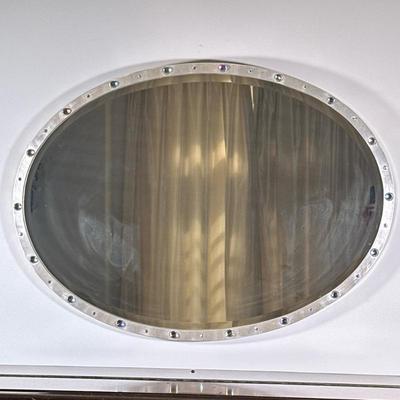 Art Deco Style Oval-Shaped Wall Mirror | Art Deco style, oval-shaped wall mirror with a metallic frame accented by gemstones. Resembles a...