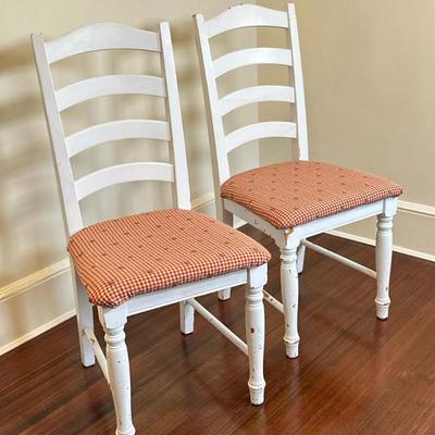 (2pc) Farmhouse Style Ladder-Back Chairs | Vintage farmhouse-style ladder-back wooden chairs, painted white with red upholstered seats. -...