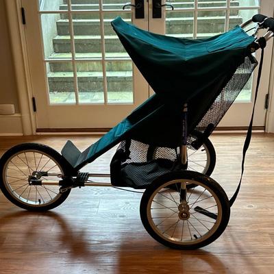 Baby Jogger Jogging Stroller | Baby Jogger jogging stroller on three wheels, with green canopy and seat. Wheels need air.
